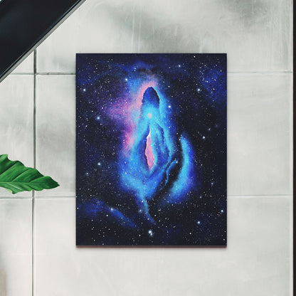 Galaxy themed vulva painting in black frame hanging on wall.