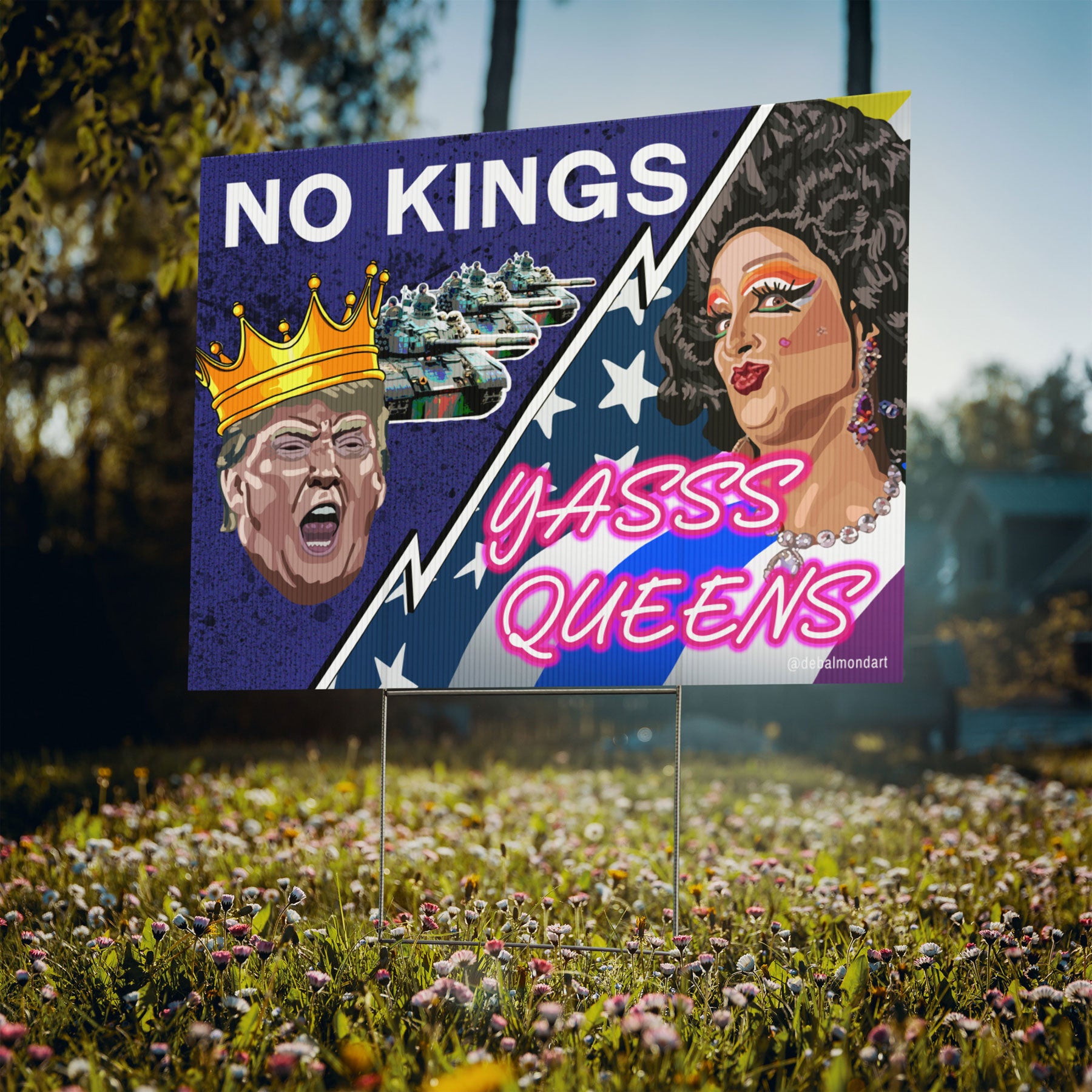 A political yard sign placed in a grassy field with wildflowers. The sign features the graphic "No Kings, Yasss Queens," which contrasts a crowned caricature of Donald Trump and military tanks, with a stylized portrait of a drag queen against a star-spangled background.