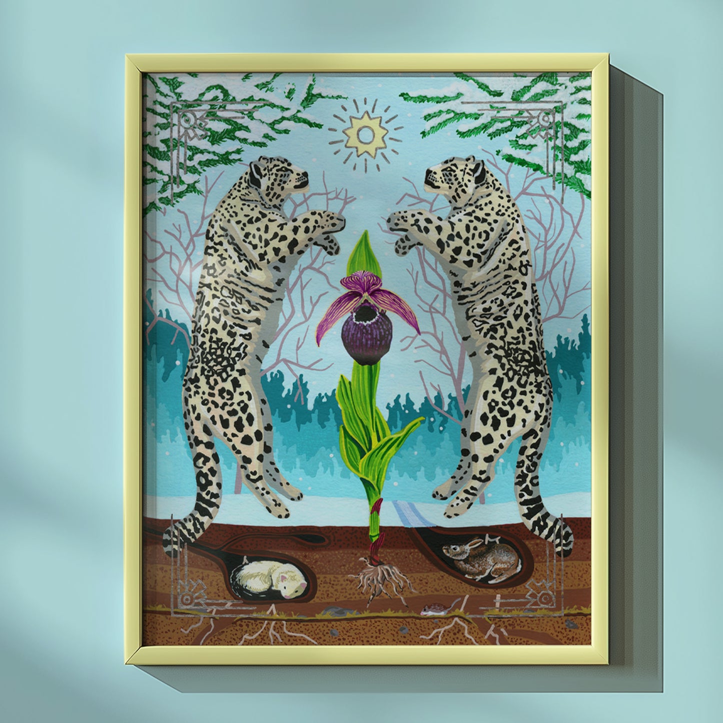 A framed art print featuring two leaping snow leopards around a purple-and-green flower, set against a light blue forest background. The print is housed in a pale yellow frame and shown hanging on a light blue wall with a soft shadow.