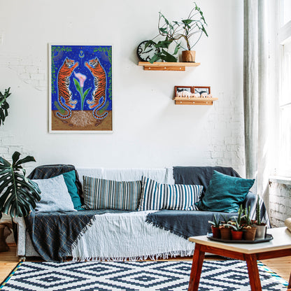 Framed tiger art print hanging on a white brick wall above a cozy grey sofa accented with blue patterned pillows, styled with wooden floating shelves, indoor plants, and a geometric rug.