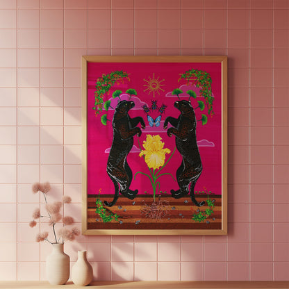A framed art print featuring two black panthers facing each other around a yellow flower on a pink background, hanging on a pink tiled wall above a wooden surface with small vases.